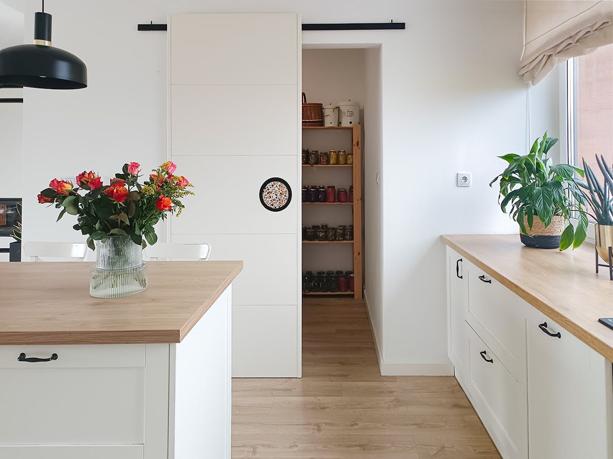 offene Schiebetür zu einer Speisekammer in einer weißen Küche