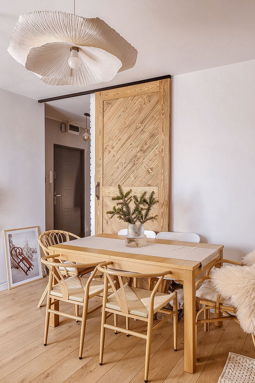 table en bois et porte en bois dans le salon aux murs blancs