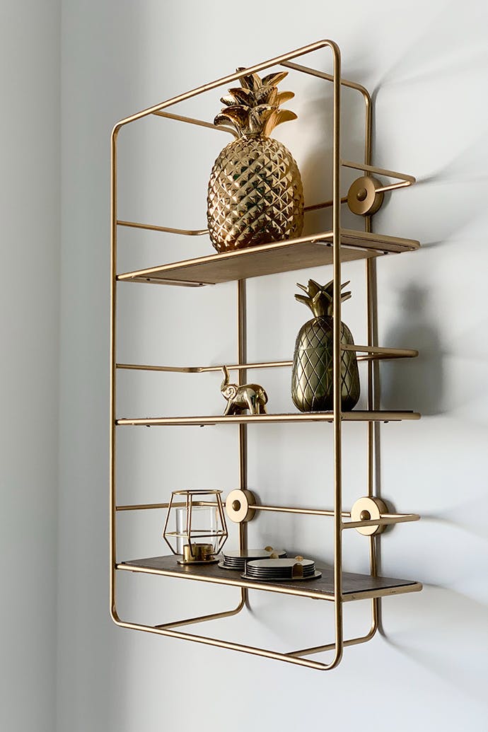 étagère dorée avec des décorations dorées sur un mur clair