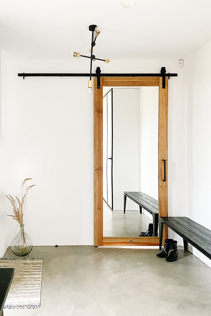 Un grand miroir avec un cadre en bois dans le vestibule avec des murs blancs et des éléments décoratifs noirs