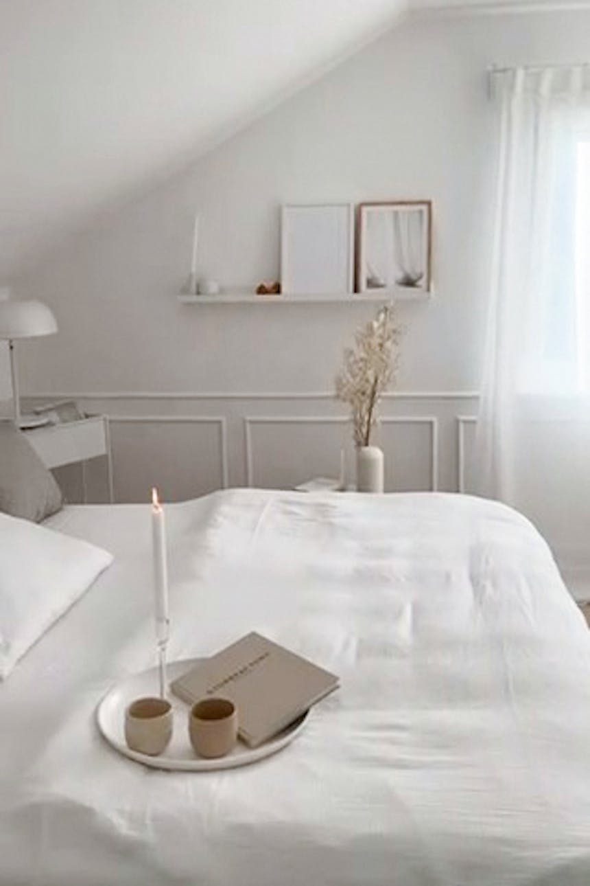 biała pościel na dużym łóżku pod skosem w sypialni na poddaszu