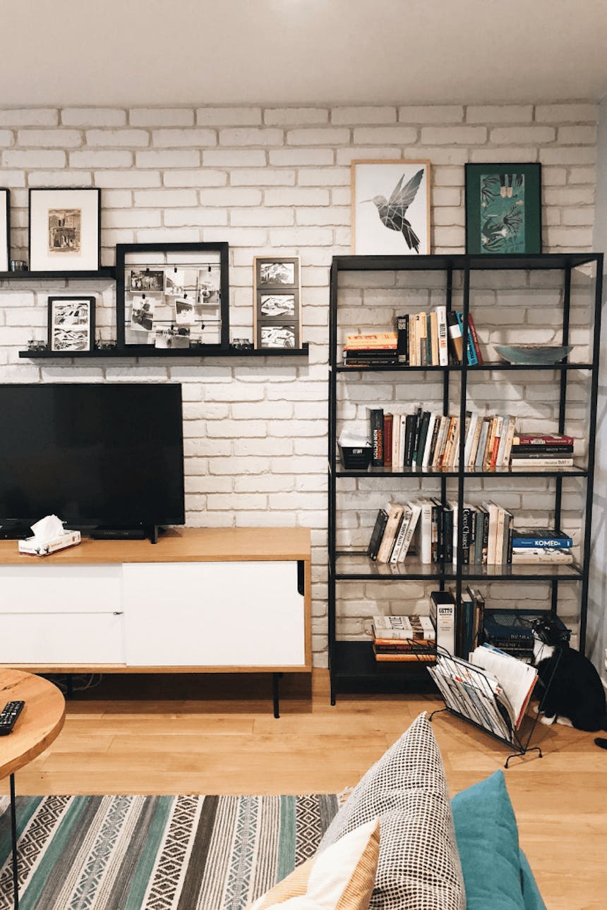 Innenraum im Industriestil, Backsteinmauer im Wohnzimmer, Bücherregal aus Metall, Wanddekorationen für das Wohnzimmer, Bilder für die Wand, Fernsehschrank im Industriestil