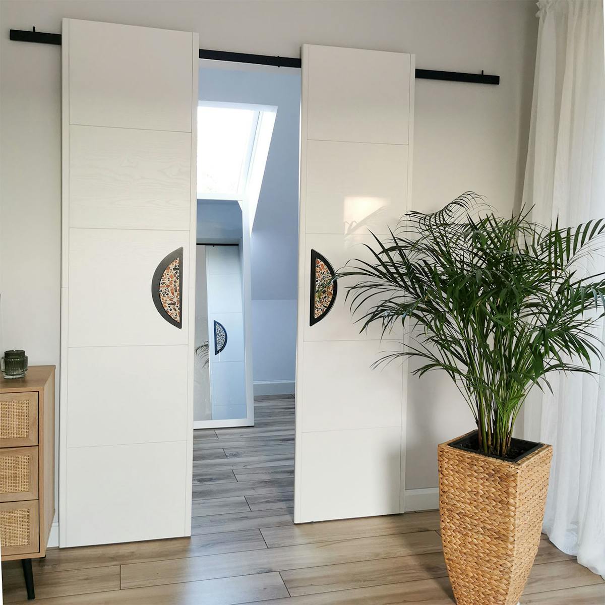 minimalistyczne, podwójne drzwi przesuwne z dużymi klamkami zamykające małą garderobę