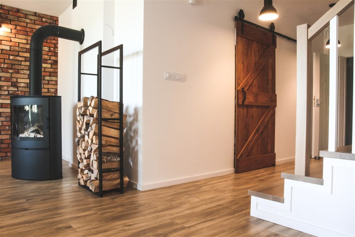 Schiebetür aus Massivholz, skandinavisches Interieur, Interieur im Loft-Stil, Küchentür, barn door, gebürstete Schiebetür, Küchenschiebetür, Backsteinmauer im Wohnzimmer, offener Raum, Kamin im Wohnzimmer