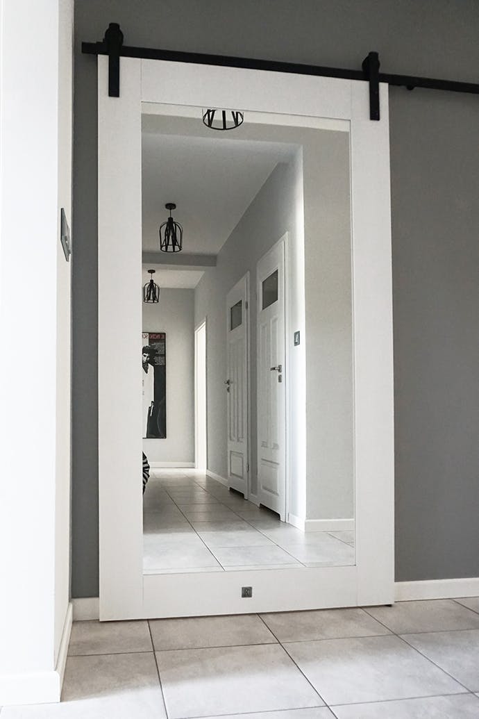 porte coulissante en bois blanc avec grand miroir et système coulissant noir
