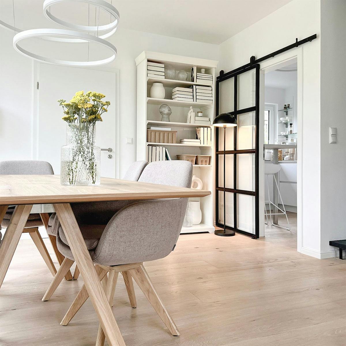 Esstisch aus Holz im nordischen Stil, moderne Lampe über Esstisch, Esszimmer kombiniert mit Küche durch Schiebetür, Metallschiebetür mit Glas