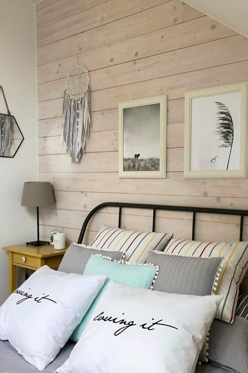 oreillers décoratifs sur le lit dans une chambre décorée dans des tons pastel