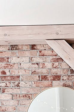 un miroir rond au-dessus d'une commode rustique contre un mur de briques dans la chambre