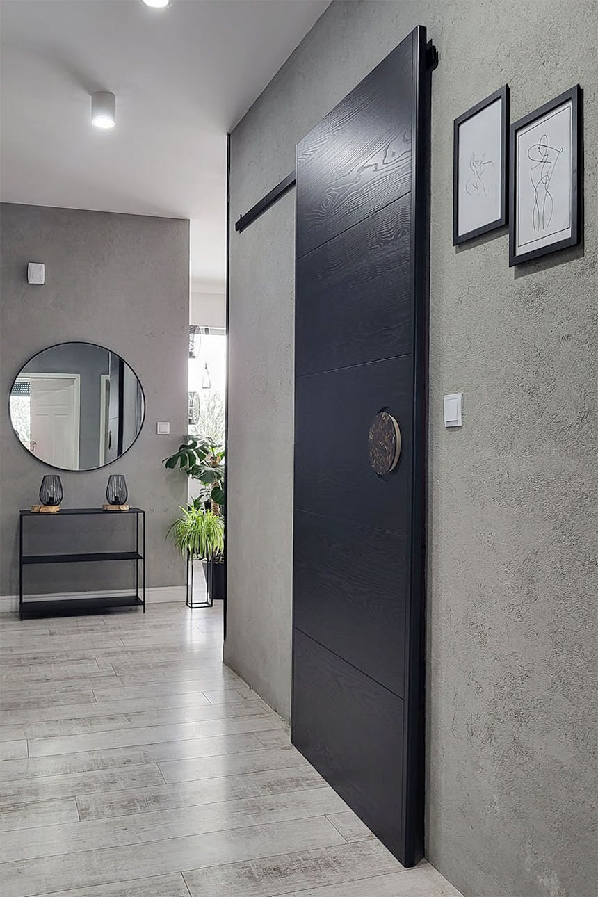 Schwarze Schiebetür im Eingang zum Badezimmer im Flur mit grauen Wänden
