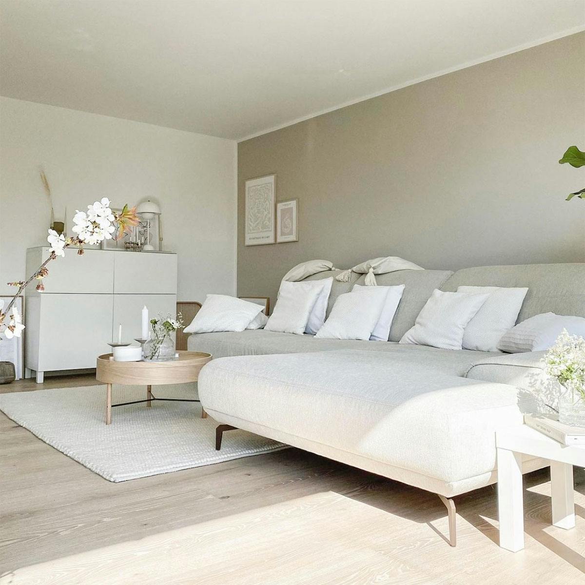 großes beiges Sofa mit weißen Kissen, Wohnzimmer im nordischen Stil, weiße Kommode im Wohnzimmer, skandinavischer Stil