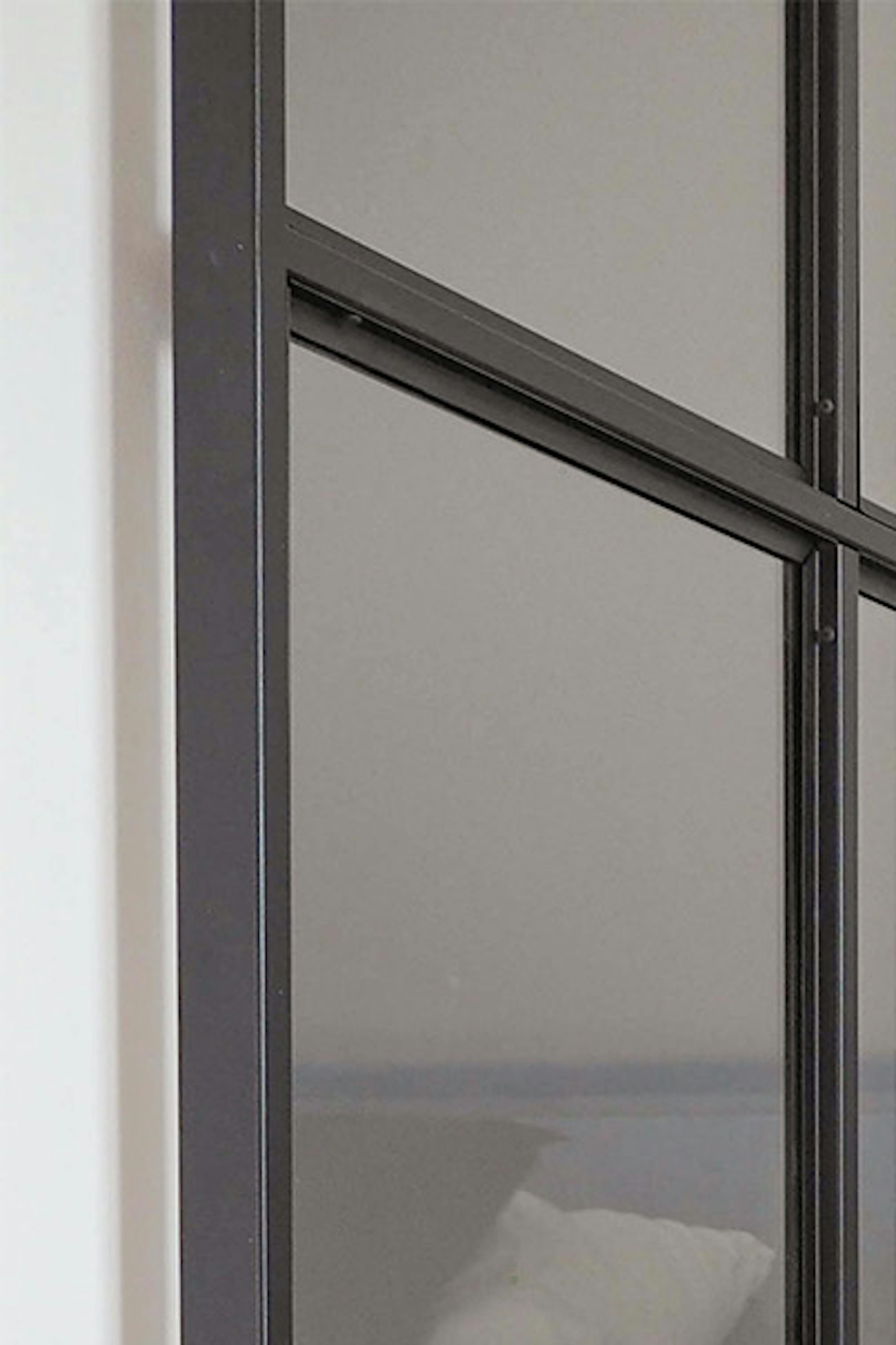portes coulissantes en verre dans un cadre en métal noir à l'entrée de la dressing mansardée