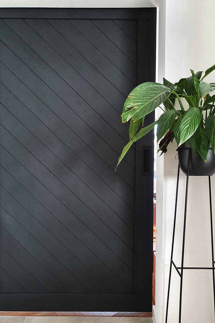 un grand parterre de fleurs en métal à côté d'une porte en bois noir