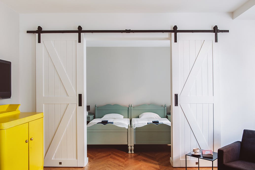 porte de chambre coulissante à double battant blanc dans un grand lit de couleur sauge
