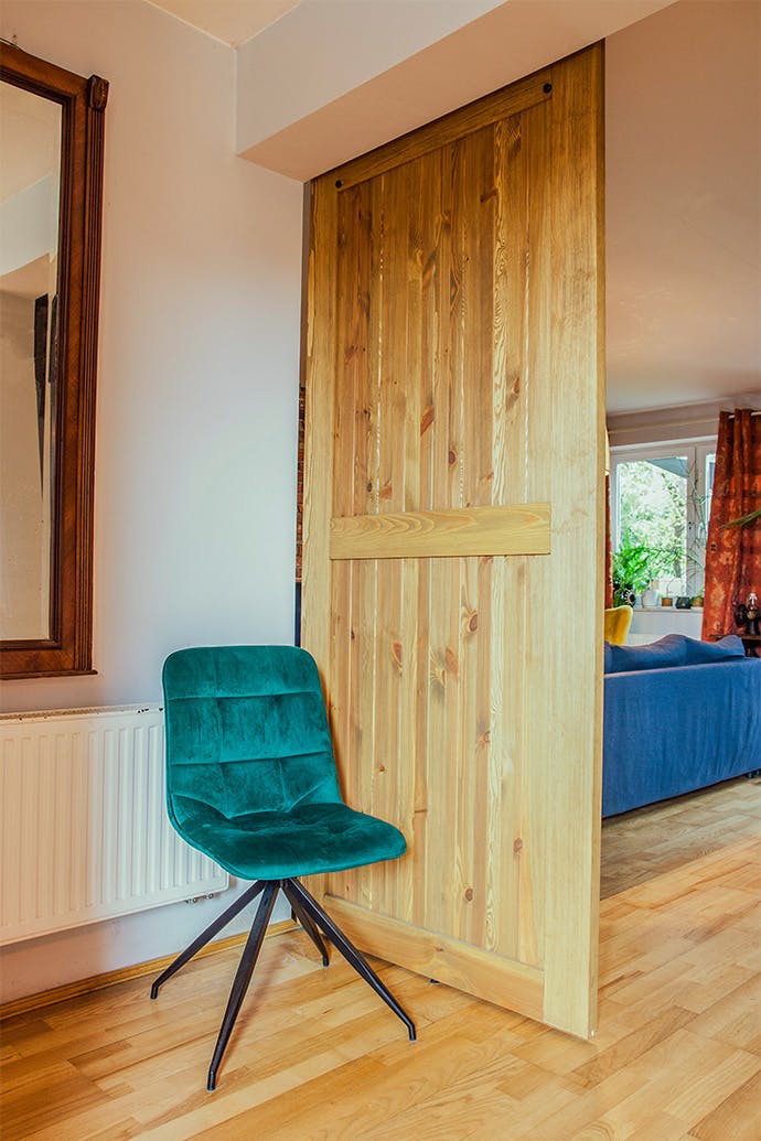 une chaise émeraude à côté d'une porte coulissante en bois