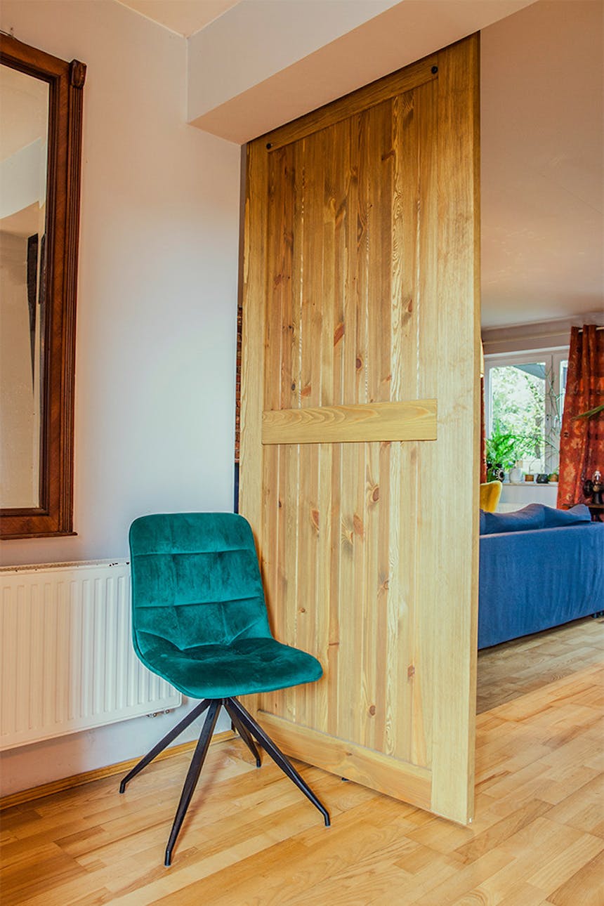 rustikale Holztür, Schiebetür aus gebürstetem Holz, barn door, grüner Veloursstuhl