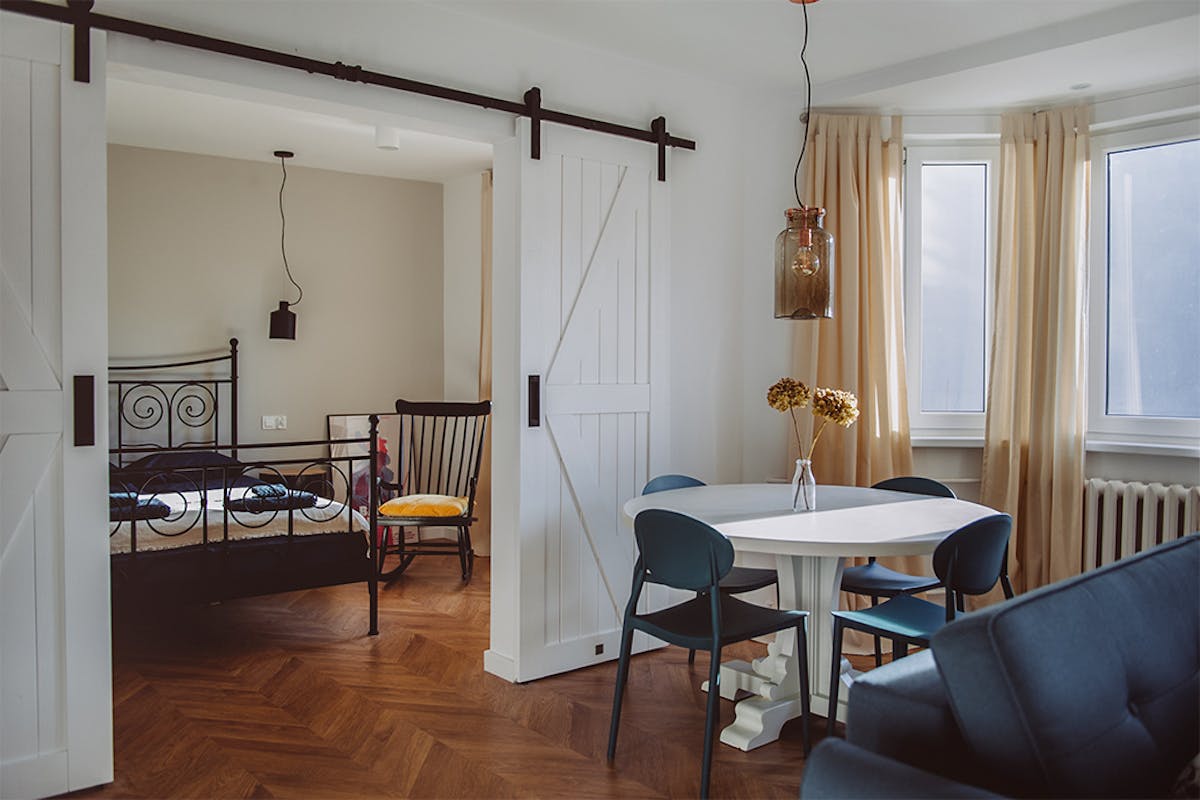 doppelte weiße Schiebetüren, die das Wohn- und Schlafzimmer in einer Wohnungseinrichtung trennen