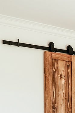 couvre-lit beige et oreillers décoratifs dans la chambre avec une petite armoire cachée derrière des portes coulissantes