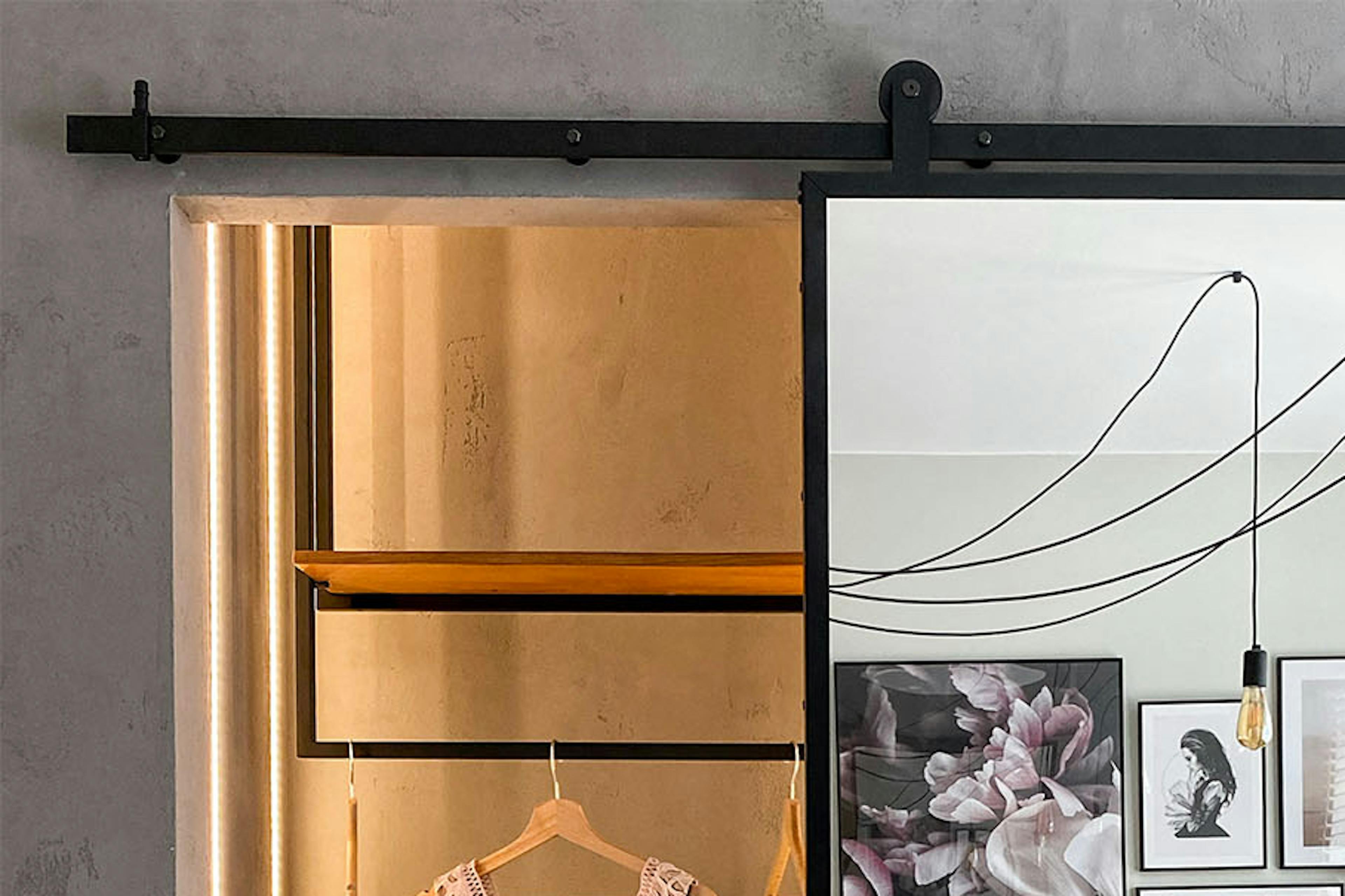 portes coulissantes dans un cadre en métal noir fermant une petite armoire en alcôve de style loft