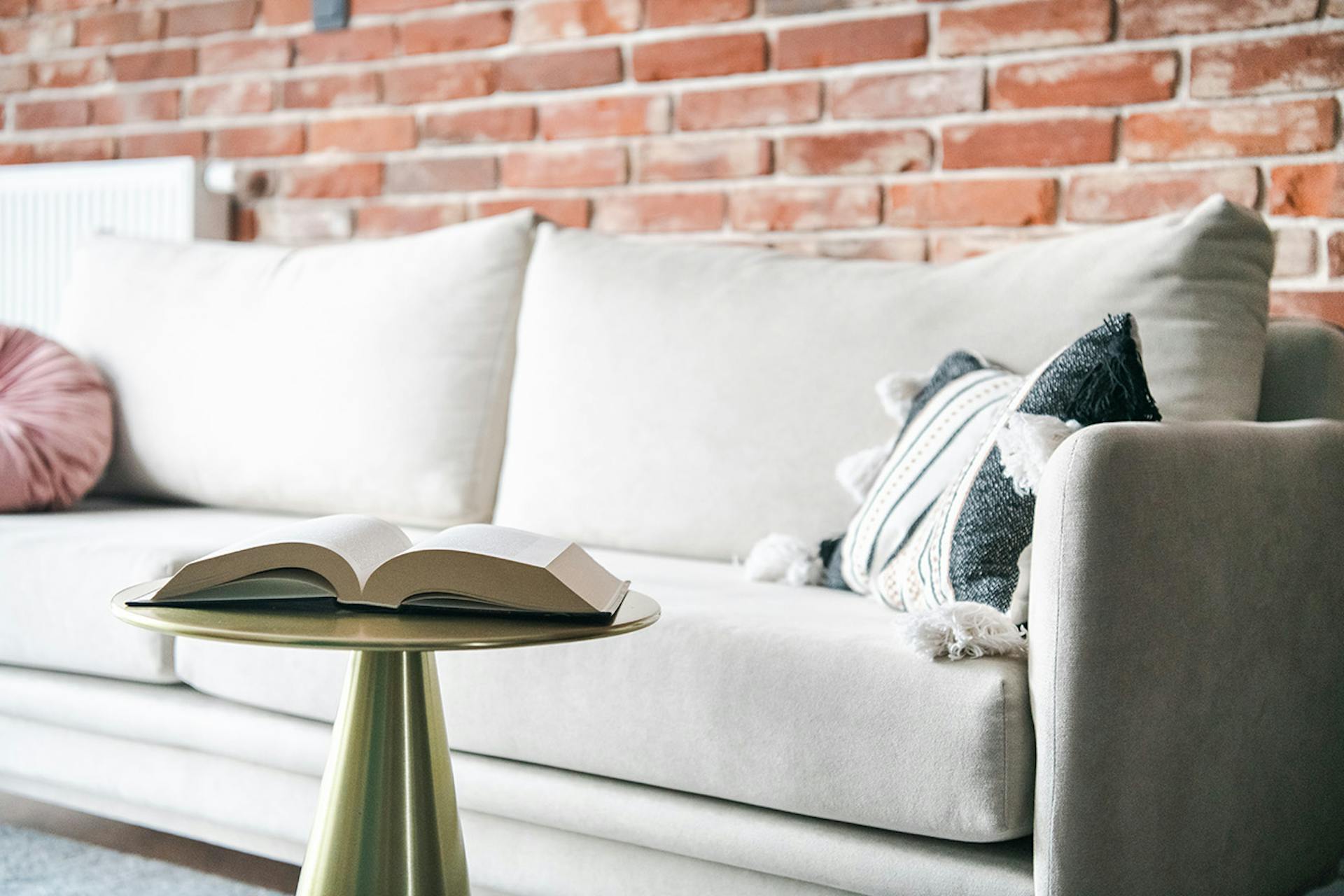 jasna sofa i czerwona cegła na ścianie w salonie