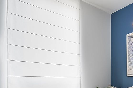 Canapé gris clair dans le salon avec un mur bleu décoré de grandes affiches