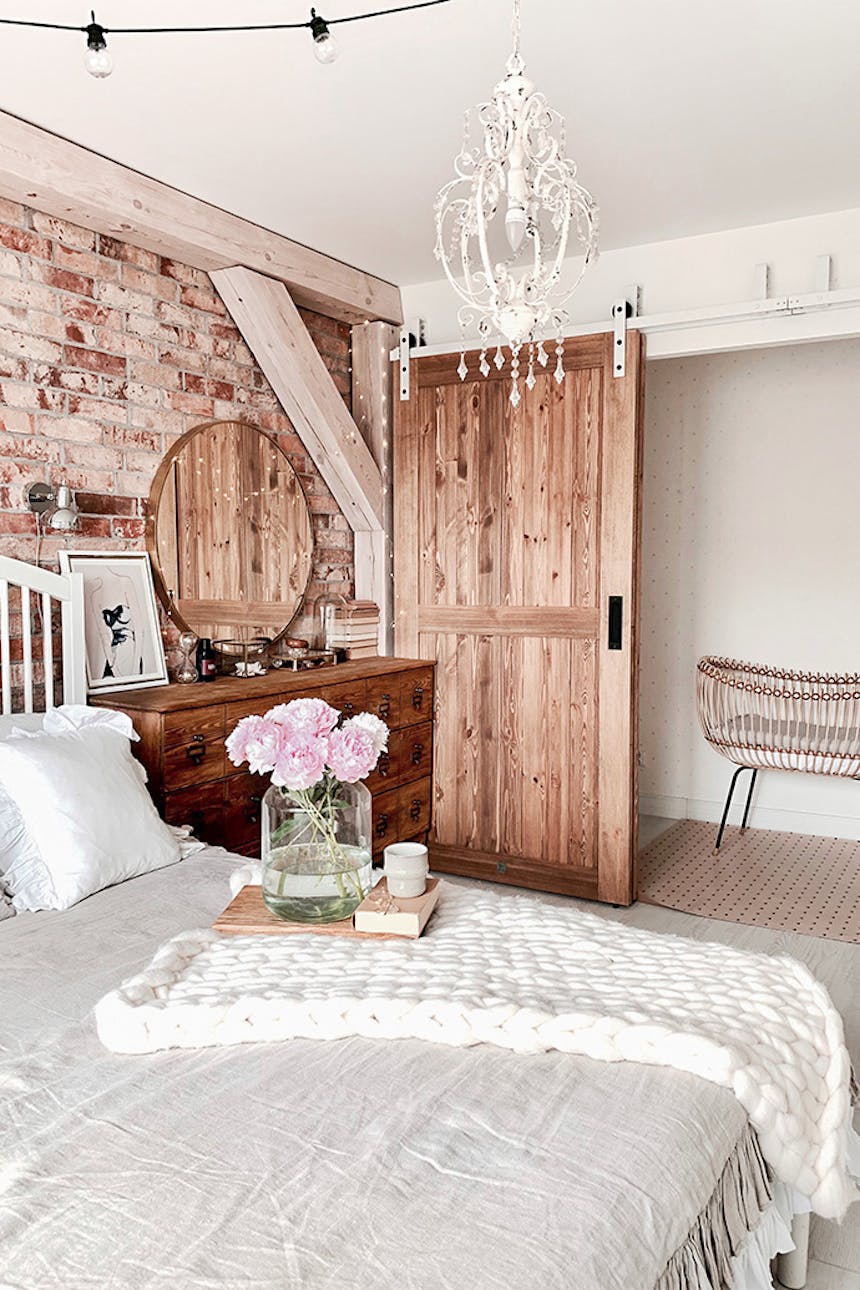 Rustikal Schlafzimmer, Holzschiebetüren, Bypass Schiebetüren, Bypass Wandhalterung für Schiebetüren, rustikaler Stil im Innenraum, moderner rustikaler Stil, Scheunen-Schiebetüren, weiße Schiebesystem, Backsteinmauer im Schlafzimmer, Deckenbalken im Schlafzimmer, weiße rustikale Kronleuchter