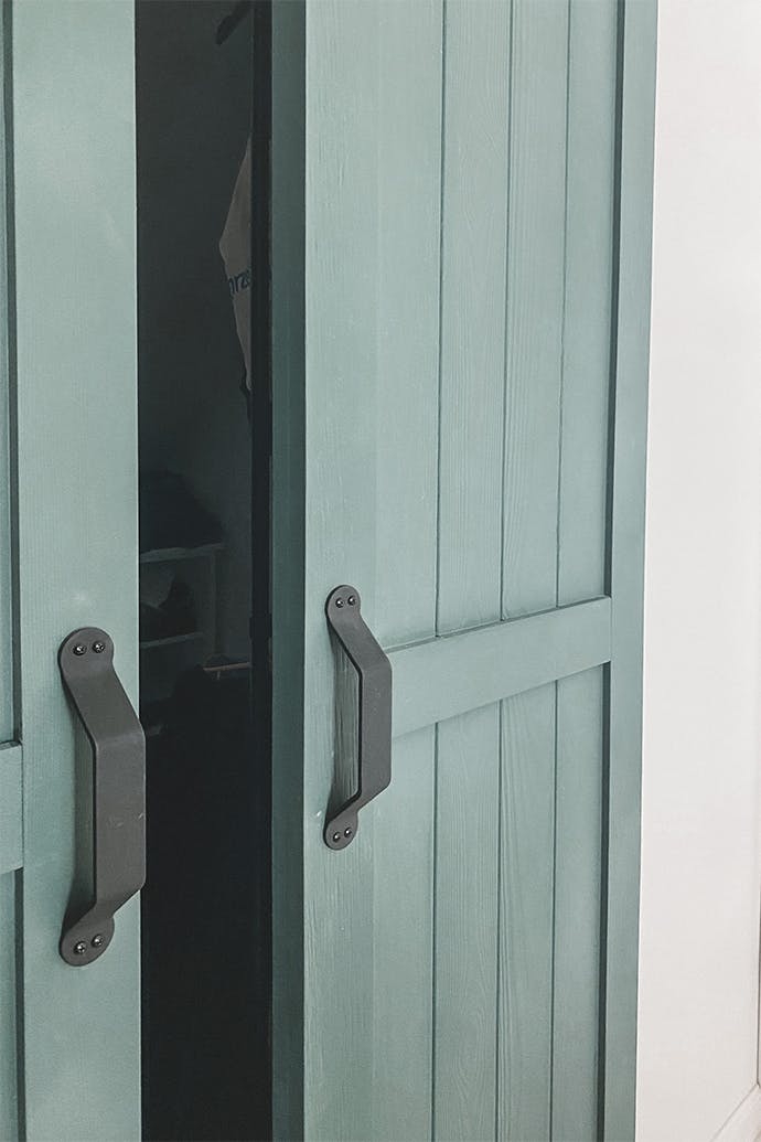 portes coulissantes étroites vertes légèrement ouvertes révélant la garde-robe