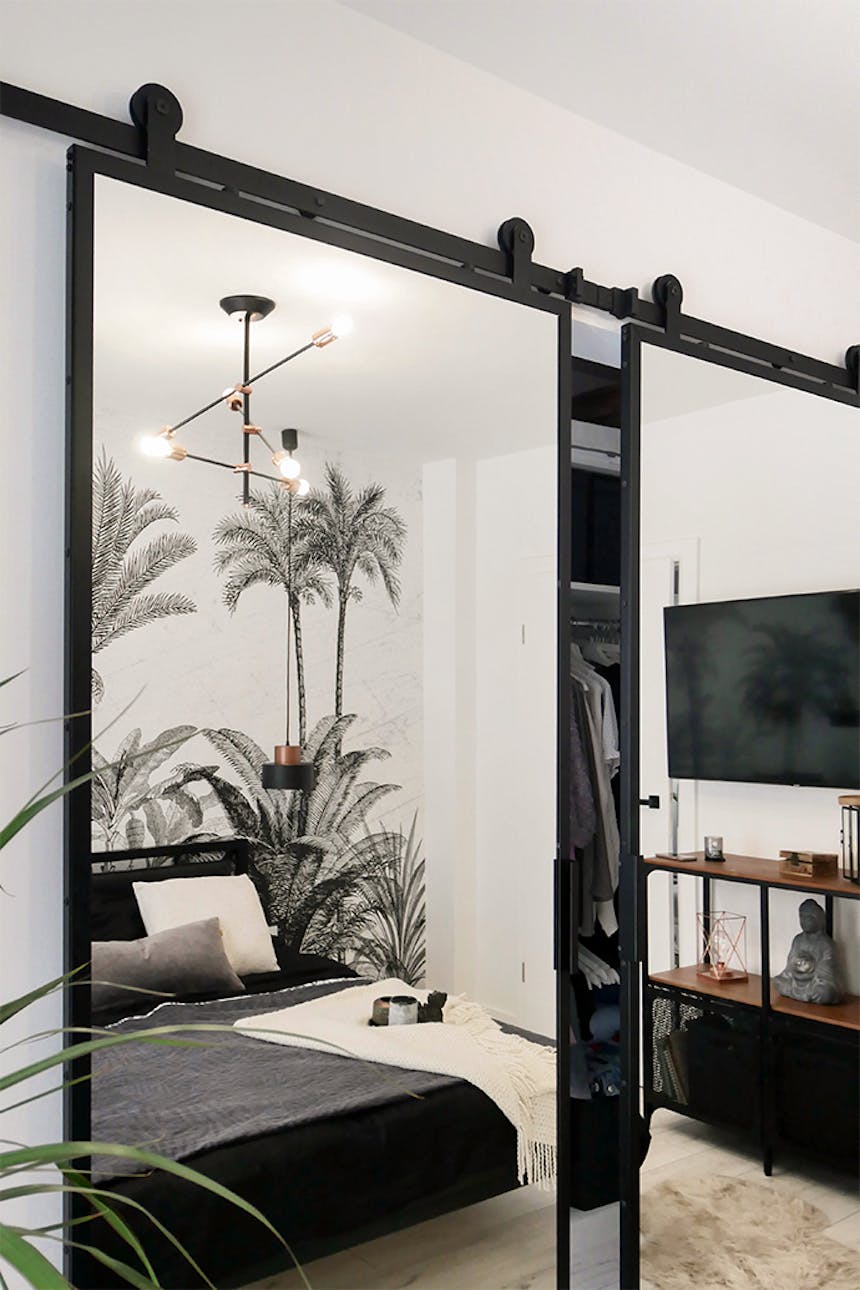 Doppel Schiebetür mit Spiegel, schwarzes Schiebesystem, Schiebetüren zum Kleiderschrank, dekorative Tapete im Schlafzimmer, industrielle Hängelampen im Schlafzimmer, großer Spiegel im Metallrahmen