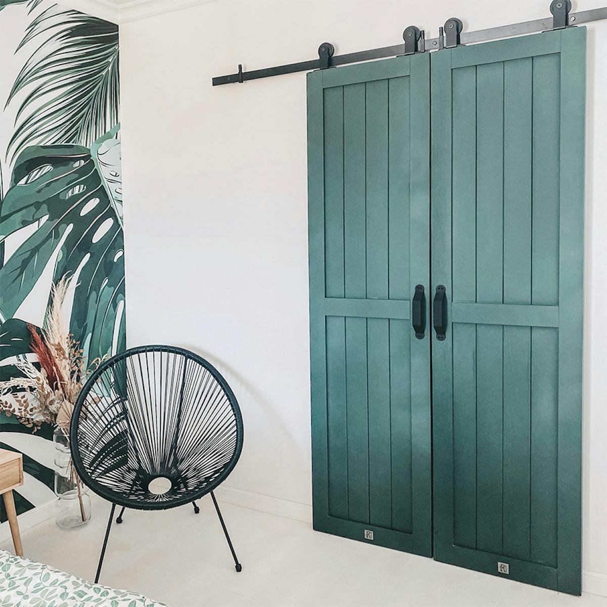 krzesło ażurowe czarne obok podwójnych zielonych drzwi przesuwnych