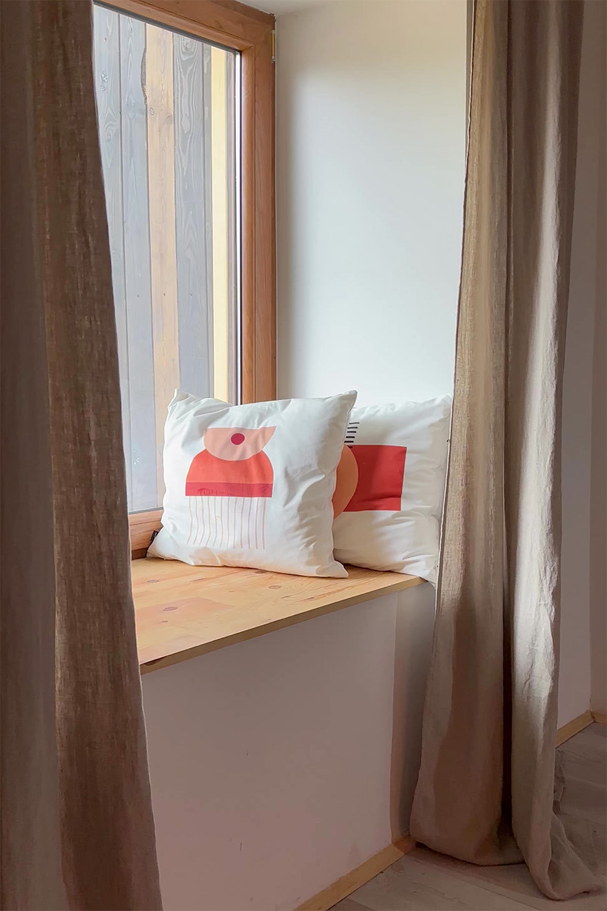 Leinenvorhänge und dekorative Kissen in der Anordnung des Sitzplatzes am Fenster