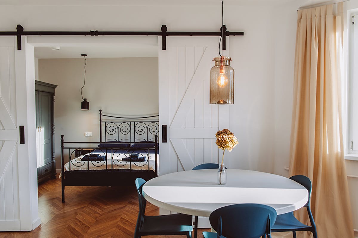 eine rustikale Lampe über einem runden Tisch und eine doppelte Schiebetür in einem Wohnungsarrangement