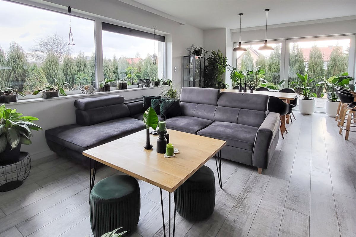 ein Wohnzimmer mit einem grauen Sofa und einem quadratischen Couchtisch aus Holz in einem grau-schwarzen Arrangement