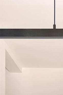 Vases décoratifs sur une grande table à manger éclairée par une longue lampe minimaliste