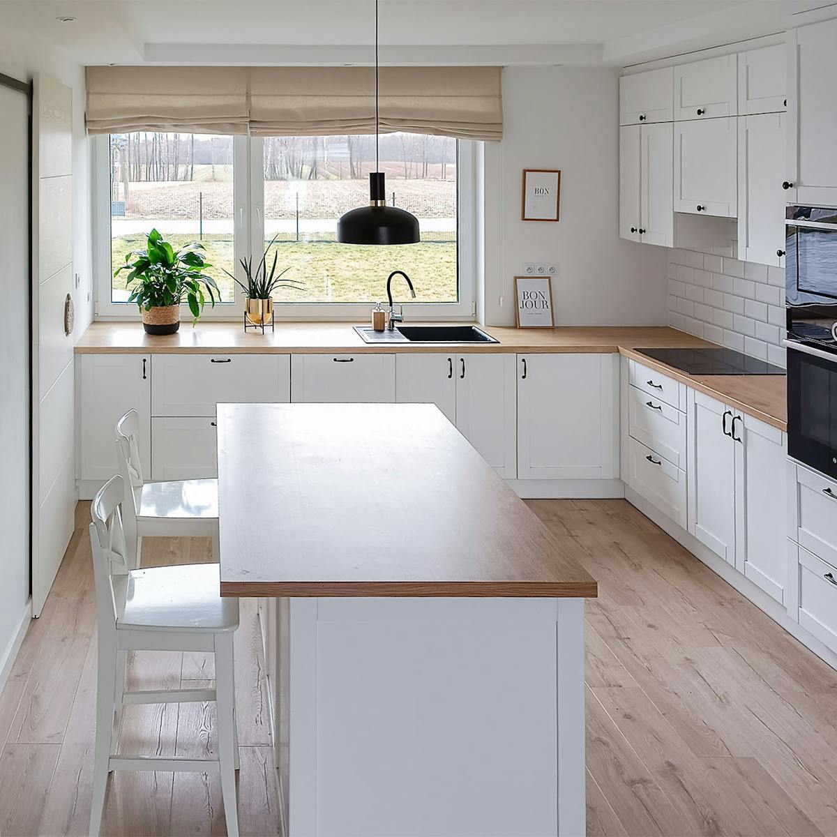 kuchnia z wyspą wykończona w bieli i drewnie