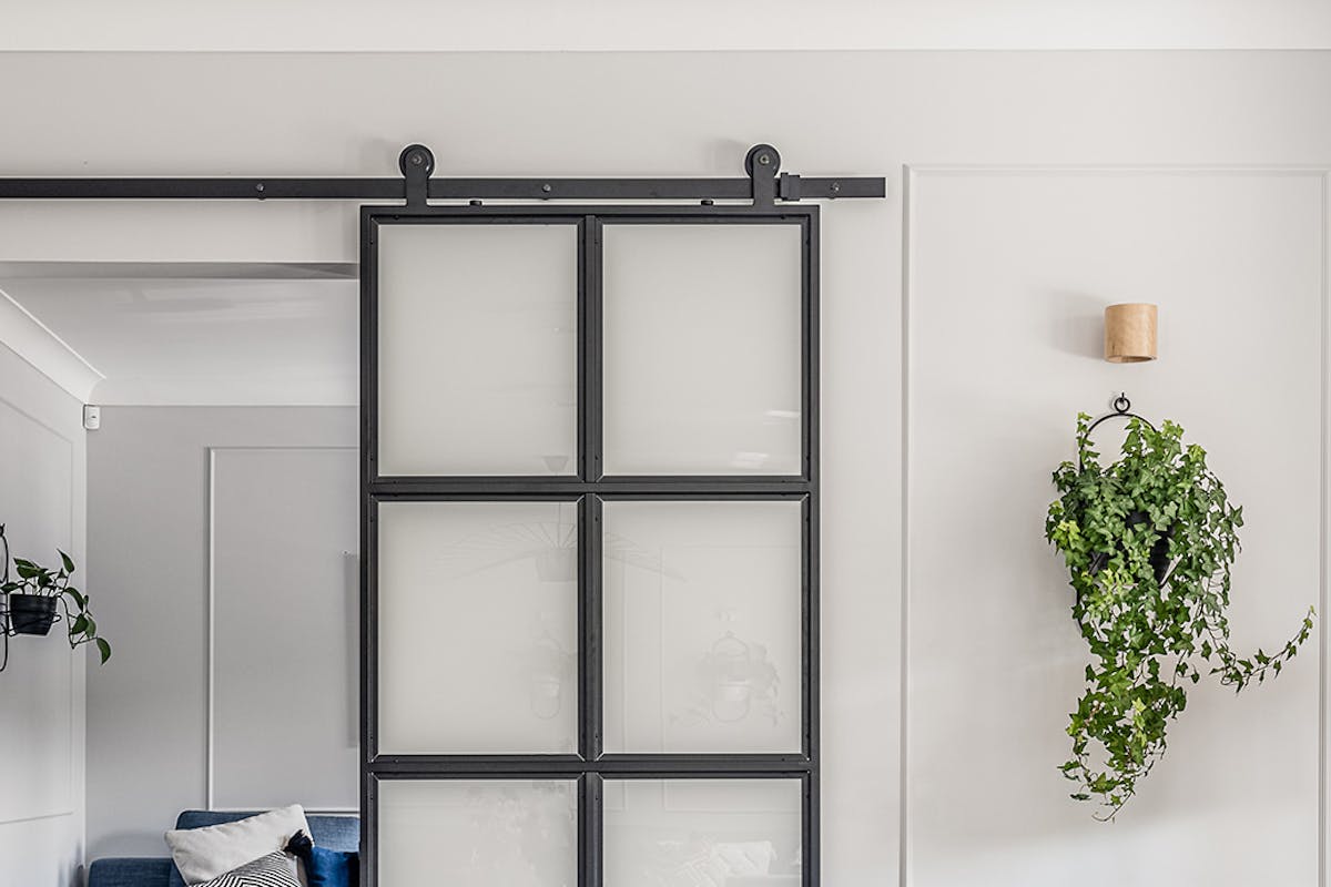 Schiebetüren aus Metall und Glas, milchiges Glas in schwarzem Metallrahmen, industrielle Schiebetüren, Blumenbeet aus Metall an der Wand