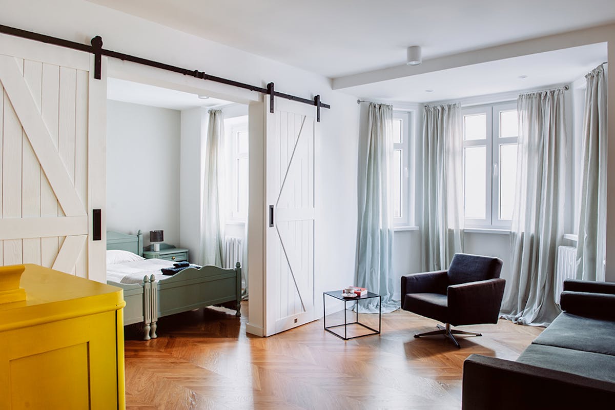 weiße Doppelschiebetüren, die das Wohnzimmer und das Schlafzimmer in der Mietwohnung trennen