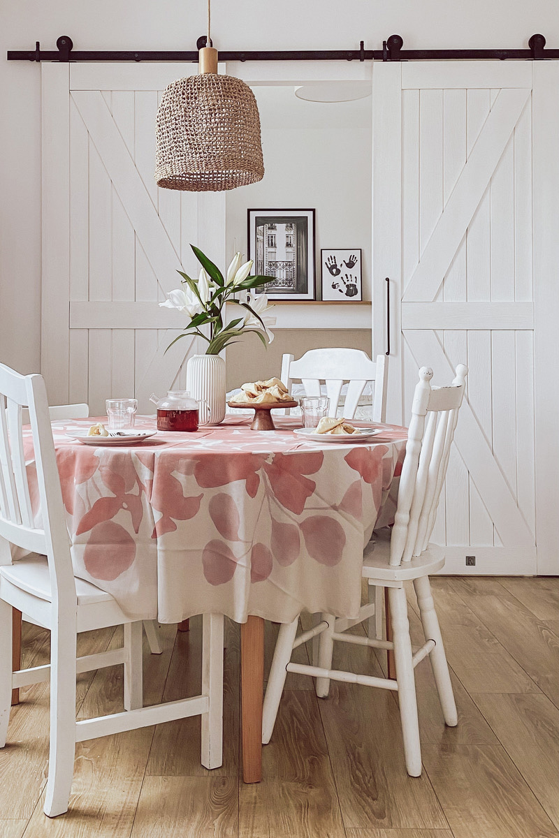 weiße Stühle am runden Tisch, Hängelampe im Boho-Stil, weiße Doppelschiebetüren im Schlafzimmer
