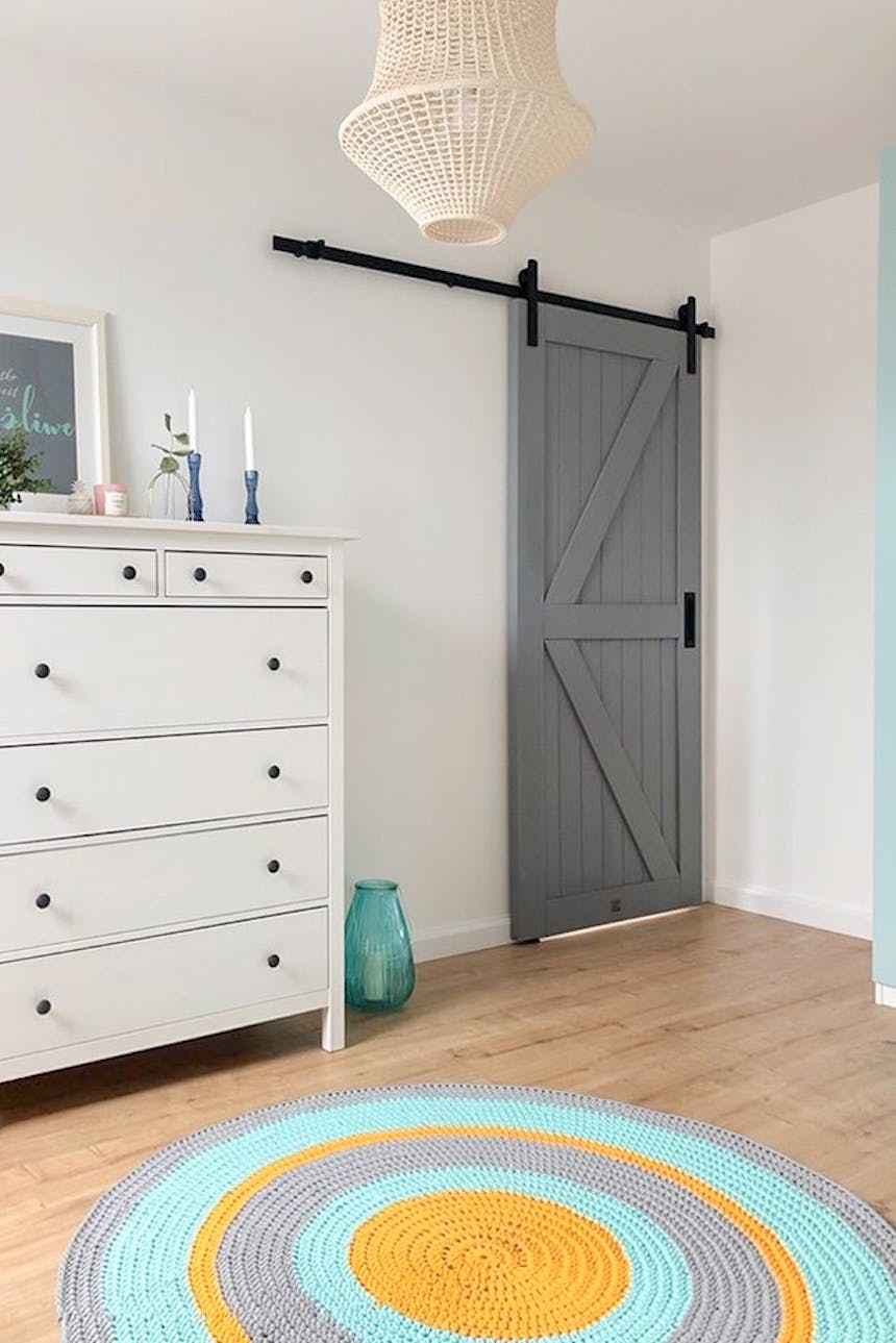 commode blanche, moquette colorée et portes coulissantes grises sur fond de murs blancs