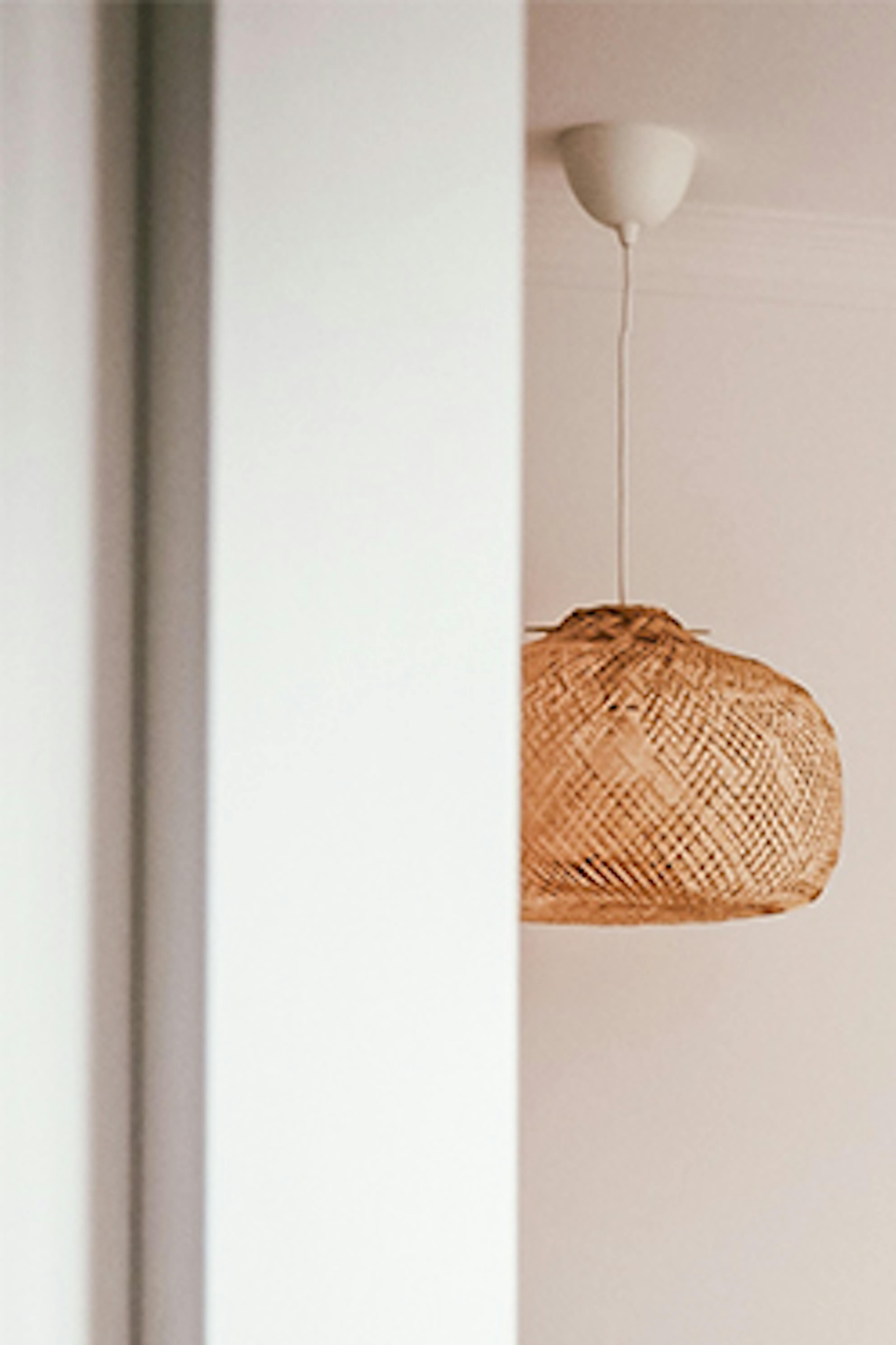 un couvre-lit beige, des coussins décoratifs et des suspensions ajourées dans une chambre de style bohème
