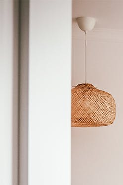 un couvre-lit beige, des coussins décoratifs et des suspensions ajourées dans une chambre de style bohème