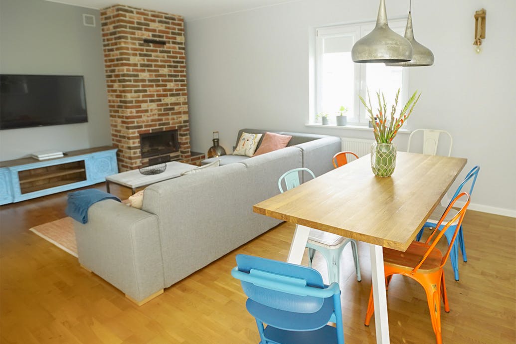 chaises colorées à la table à manger dans le salon avec canapé gris et cheminée en brique