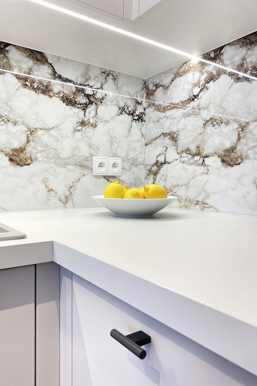 Fliesen mit Steinmotiv über der Küchenarbeitsplatte, weiße Küchenmöbel, modernes Apartment