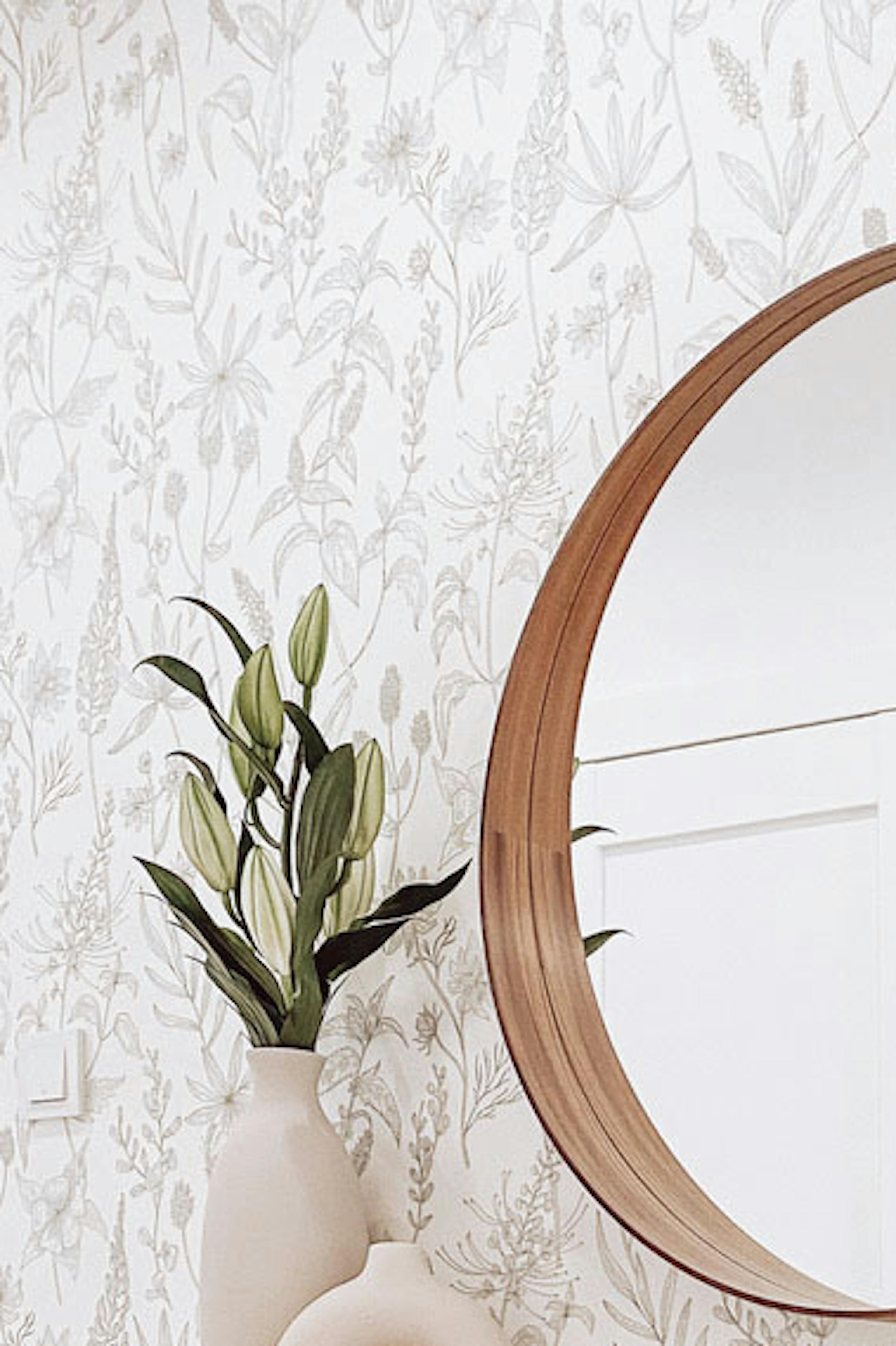 un miroir dans un cadre décoratif en bois au-dessus d'une étroite commode blanche