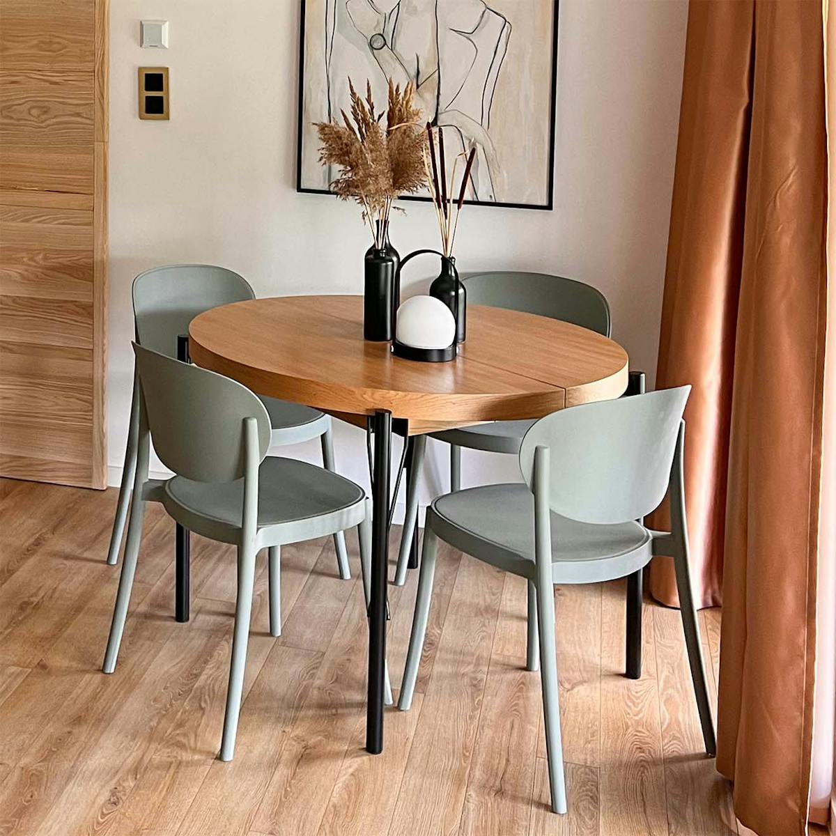 szałwiowe krzesła stojące wokół okrągłego stołu z drewnianym blatem i metalowymi nogami