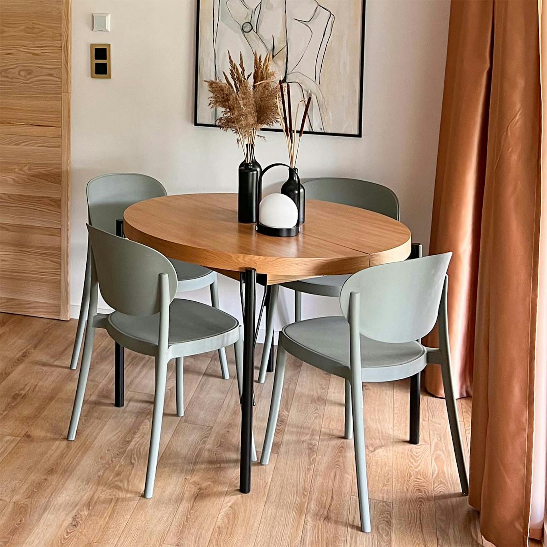 Sage-Stühle stehen um einen runden Tisch mit Holzplatte und Metallbeinen