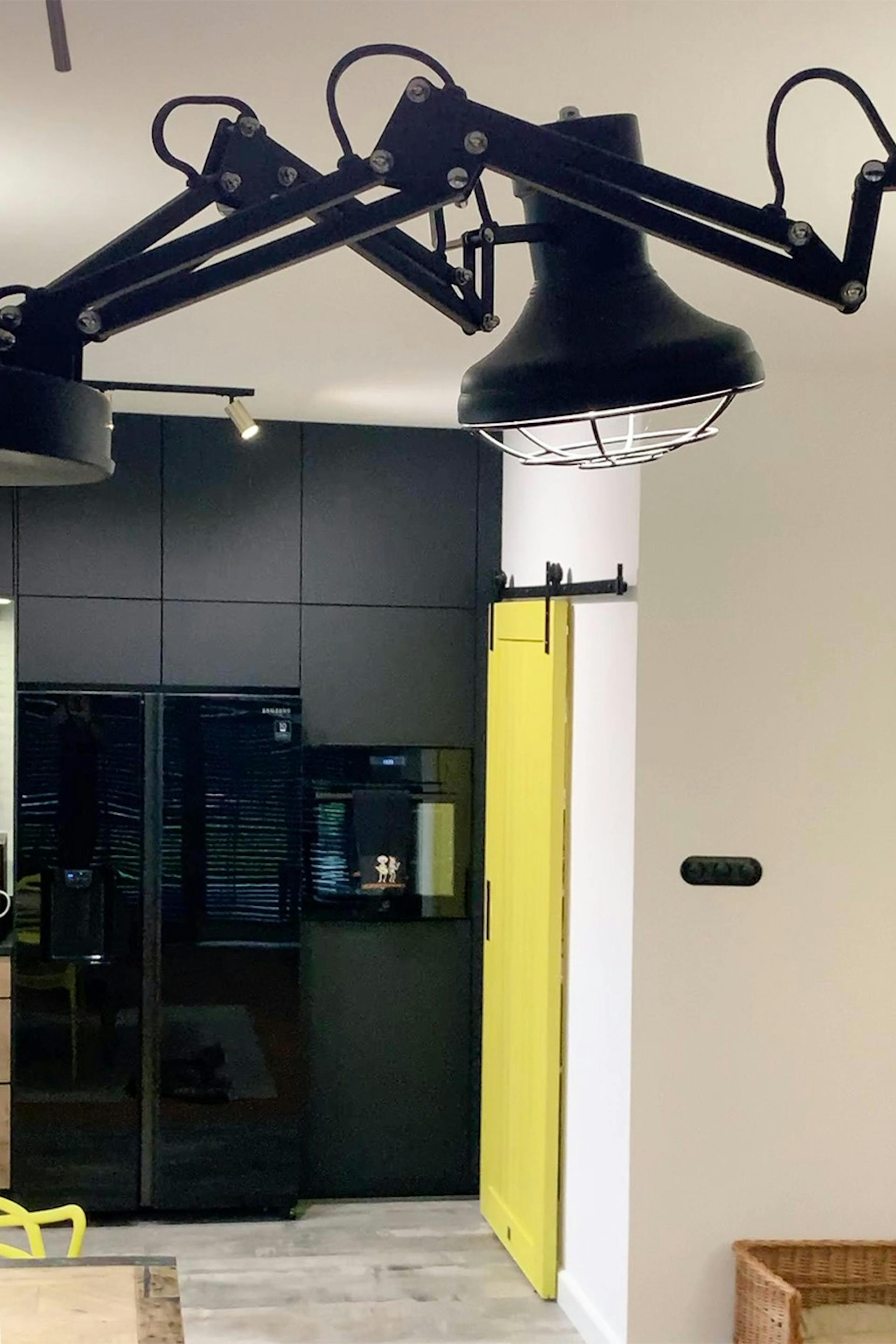 schwarze industrielle Pendelleuchte und gelbe Schiebetür in einem modernen Interieur