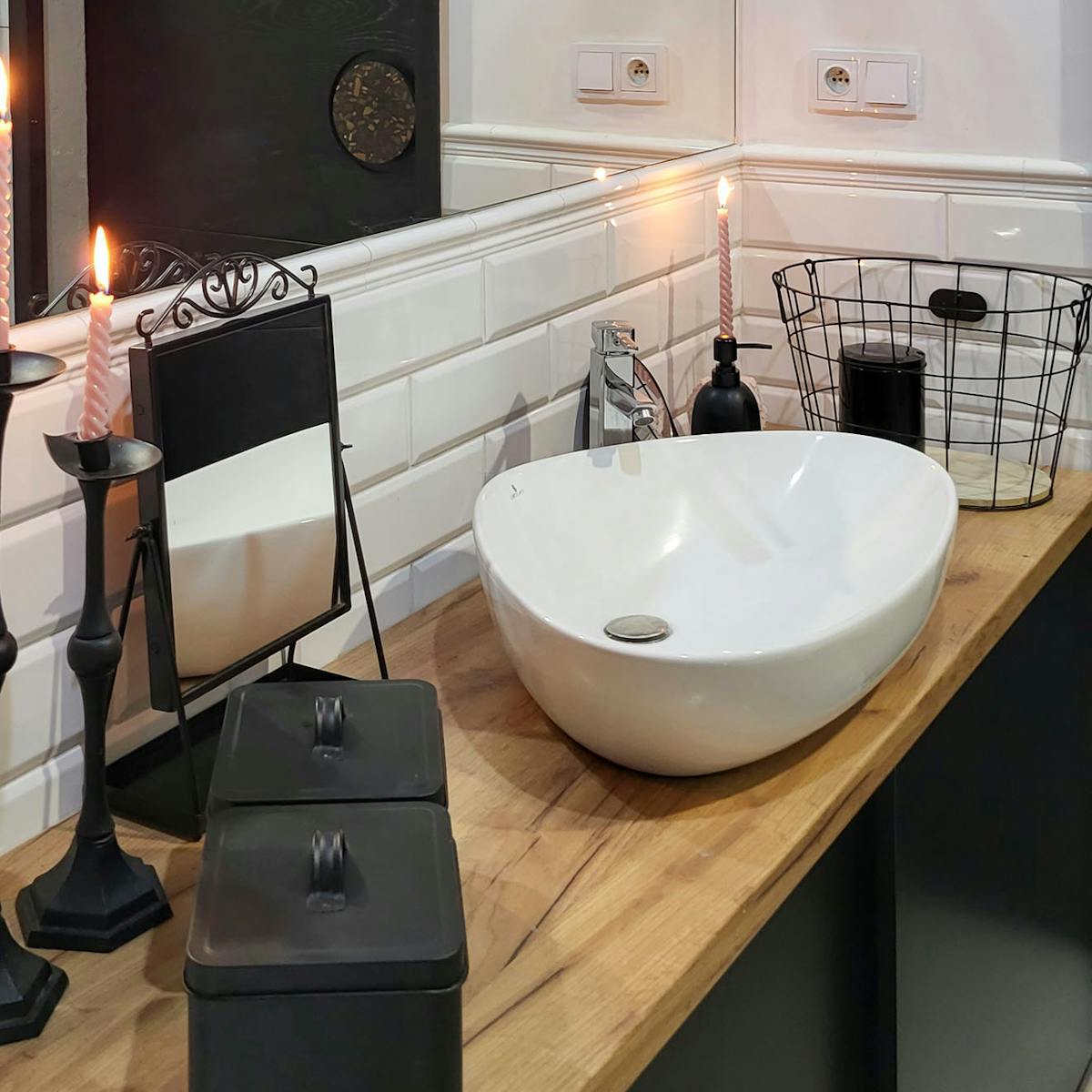 czarne akcesoria i biała umywalka na drewnianym blacie w łazience