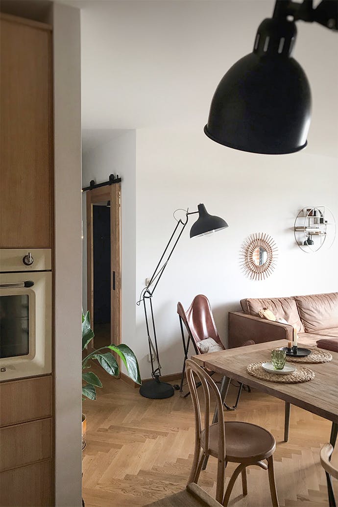 porte coulissante vers le bureau, grand lampadaire en métal, fauteuil en cuir sur socle en métal, fauteuil vintage, parquet au sol dans le salon, miroir dans le couloir