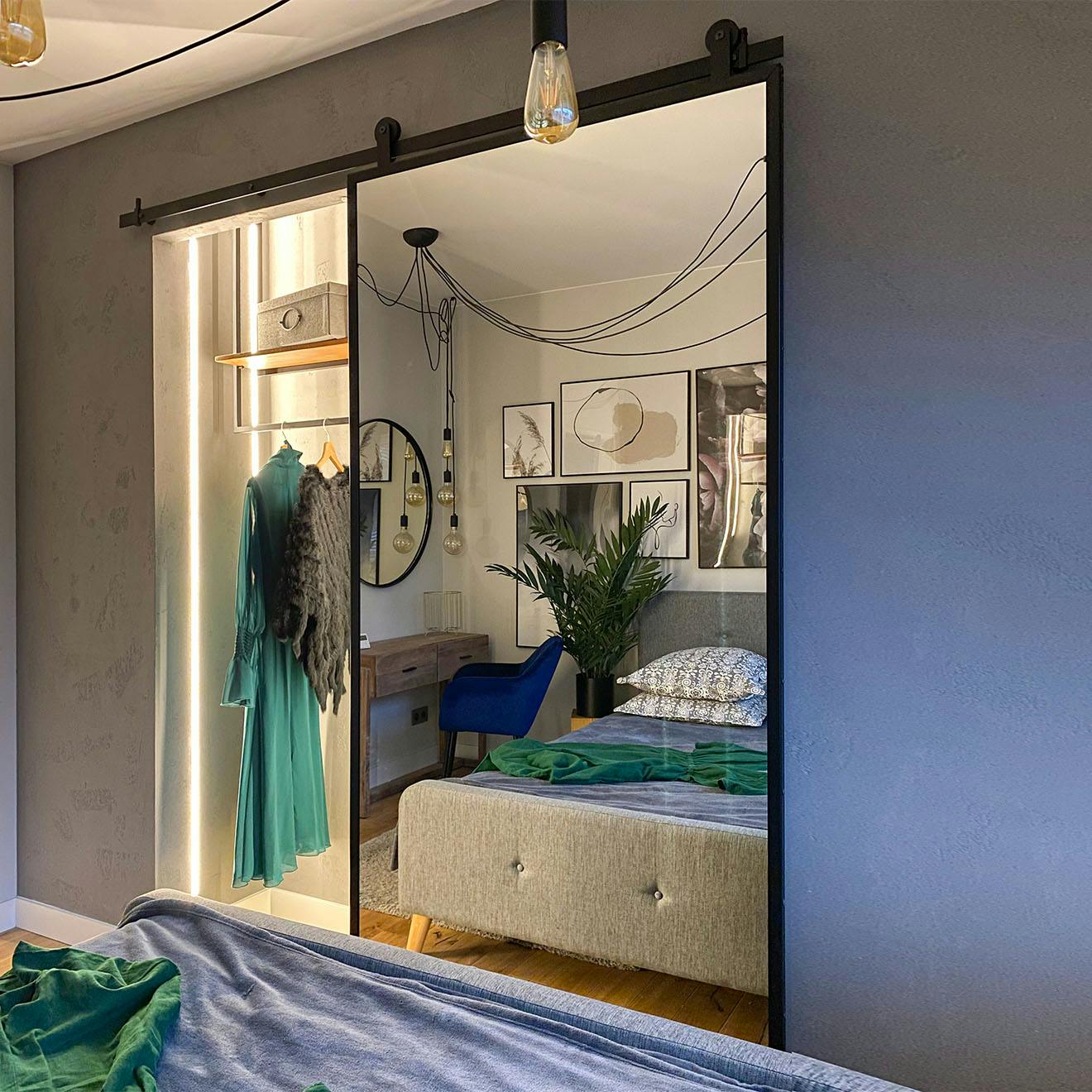 open sliding door with a mirror showing a small alcove wardrobe in the bedroom decorated in grey