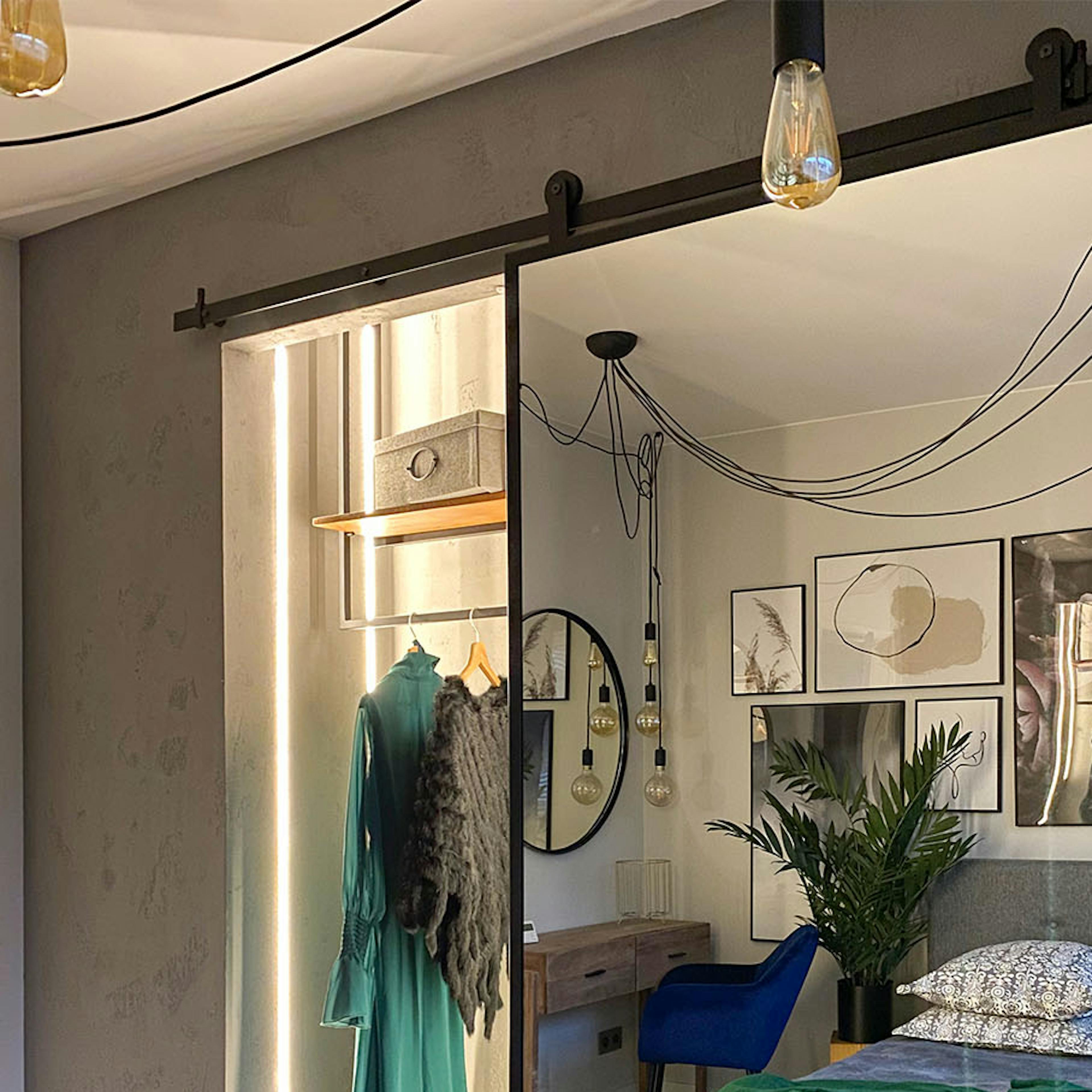porte coulissante ouverte avec un miroir montrant une petite armoire en alcôve dans la chambre décorée en gris