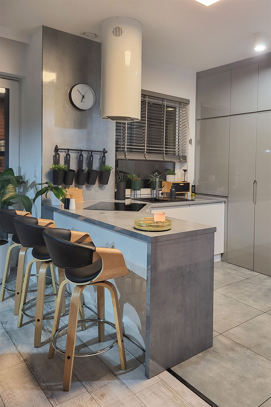 Küchenarbeitsplatte mit Barhockern, die eine moderne Küche in grauen Farben trennen